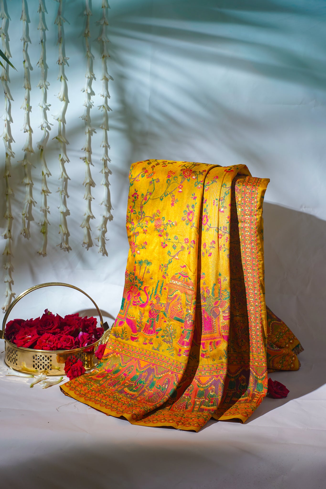 Yellow floral saree with a basket of red flowers on a white background