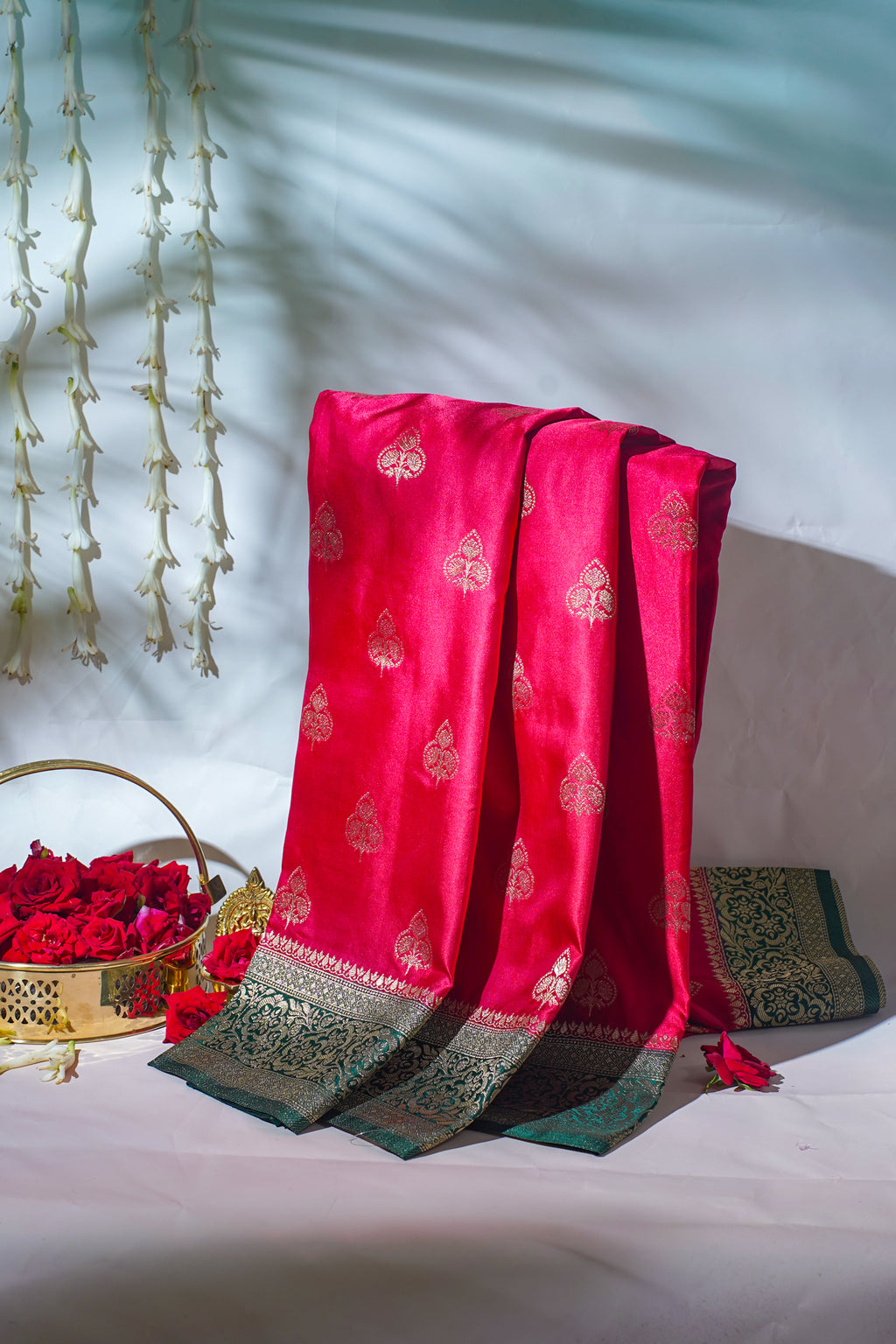 Red fabric with gold patterns draped over a white surface with decorative elements.