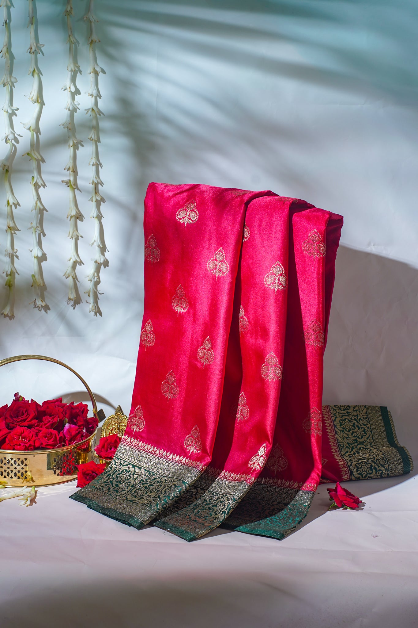 Red fabric with gold patterns draped over a white surface with decorative elements.