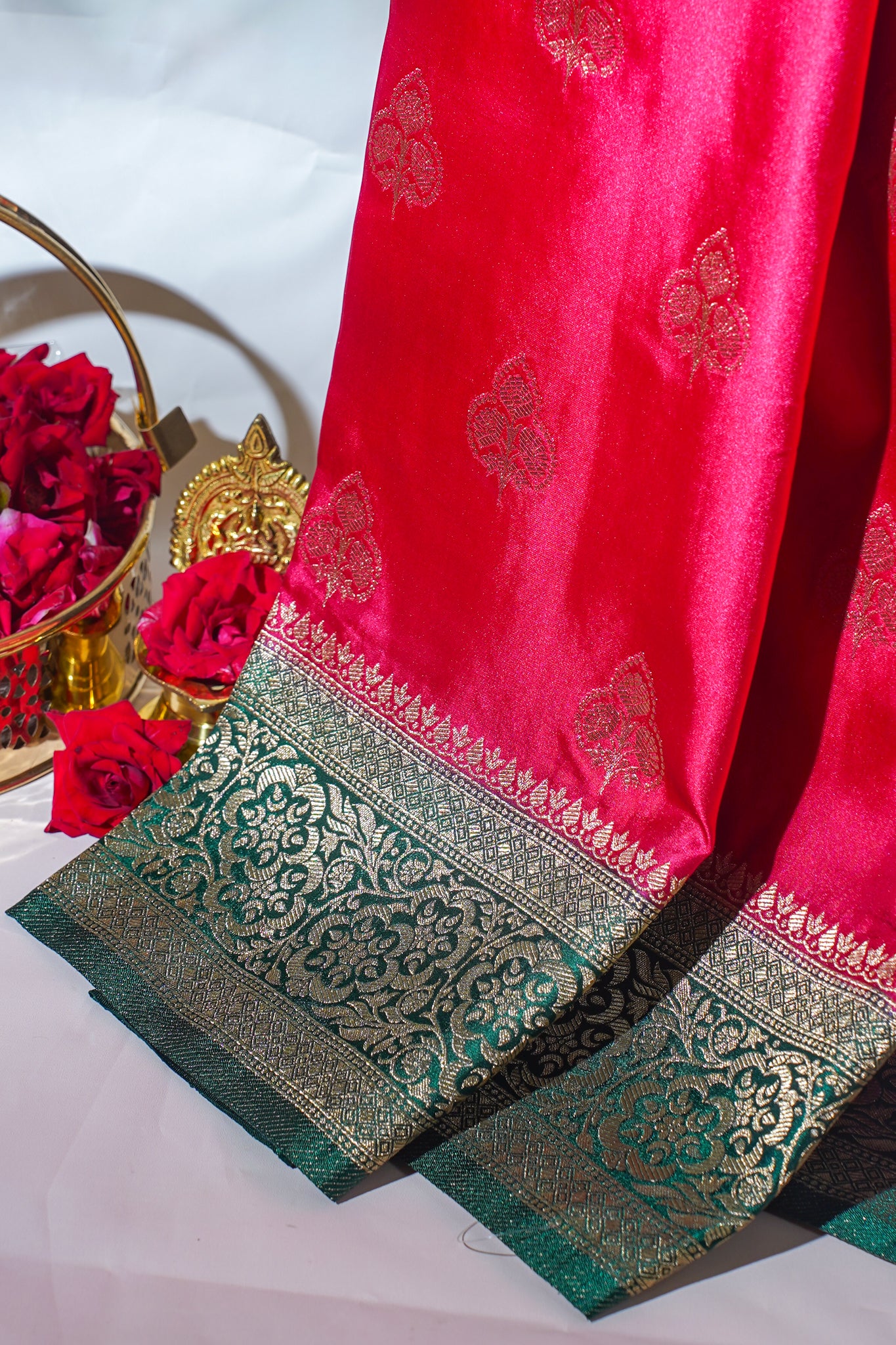 Red saree with green and gold border on a white background