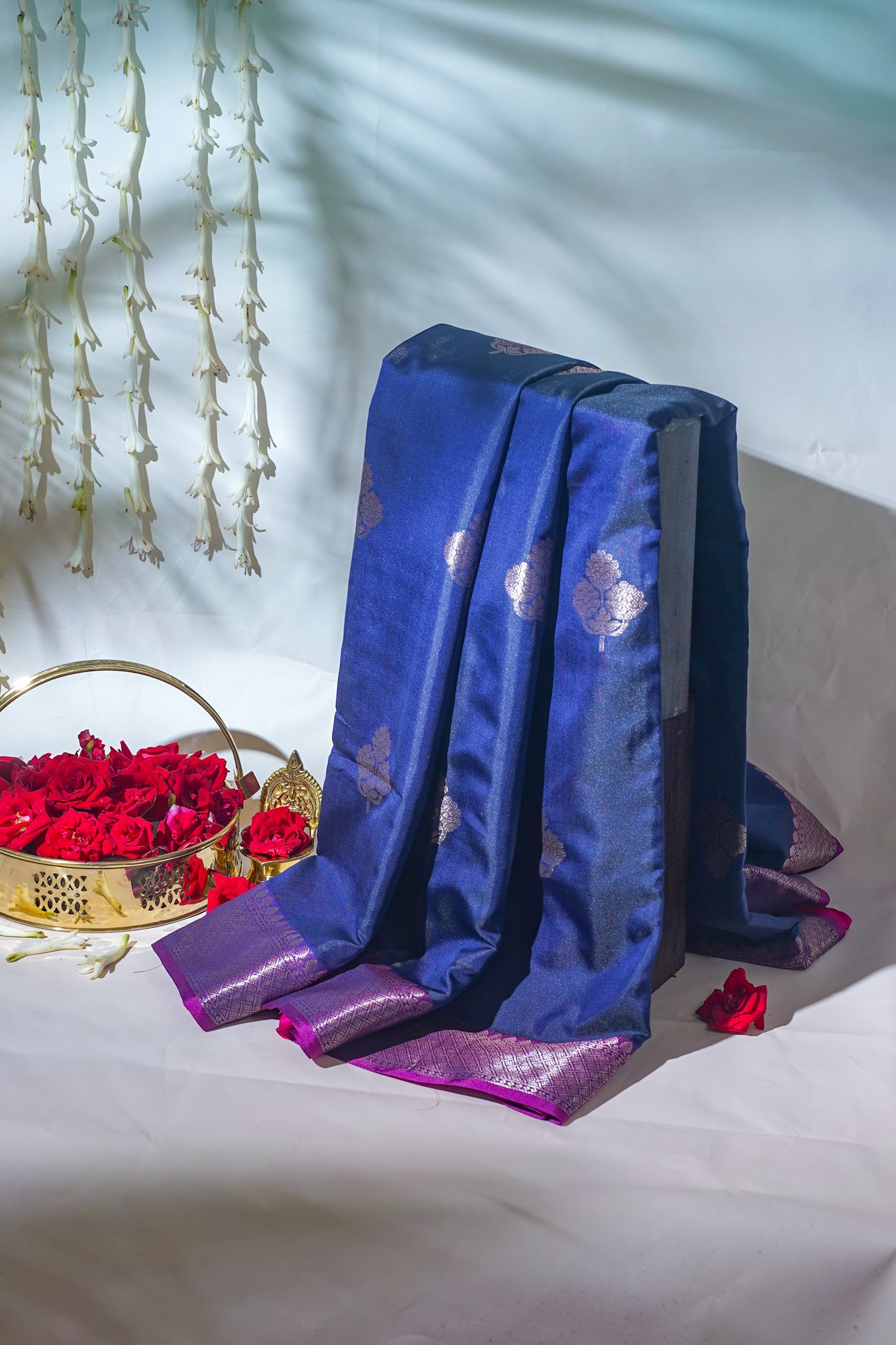 Blue fabric with purple accents on a white surface with red flowers and a decorative basket.