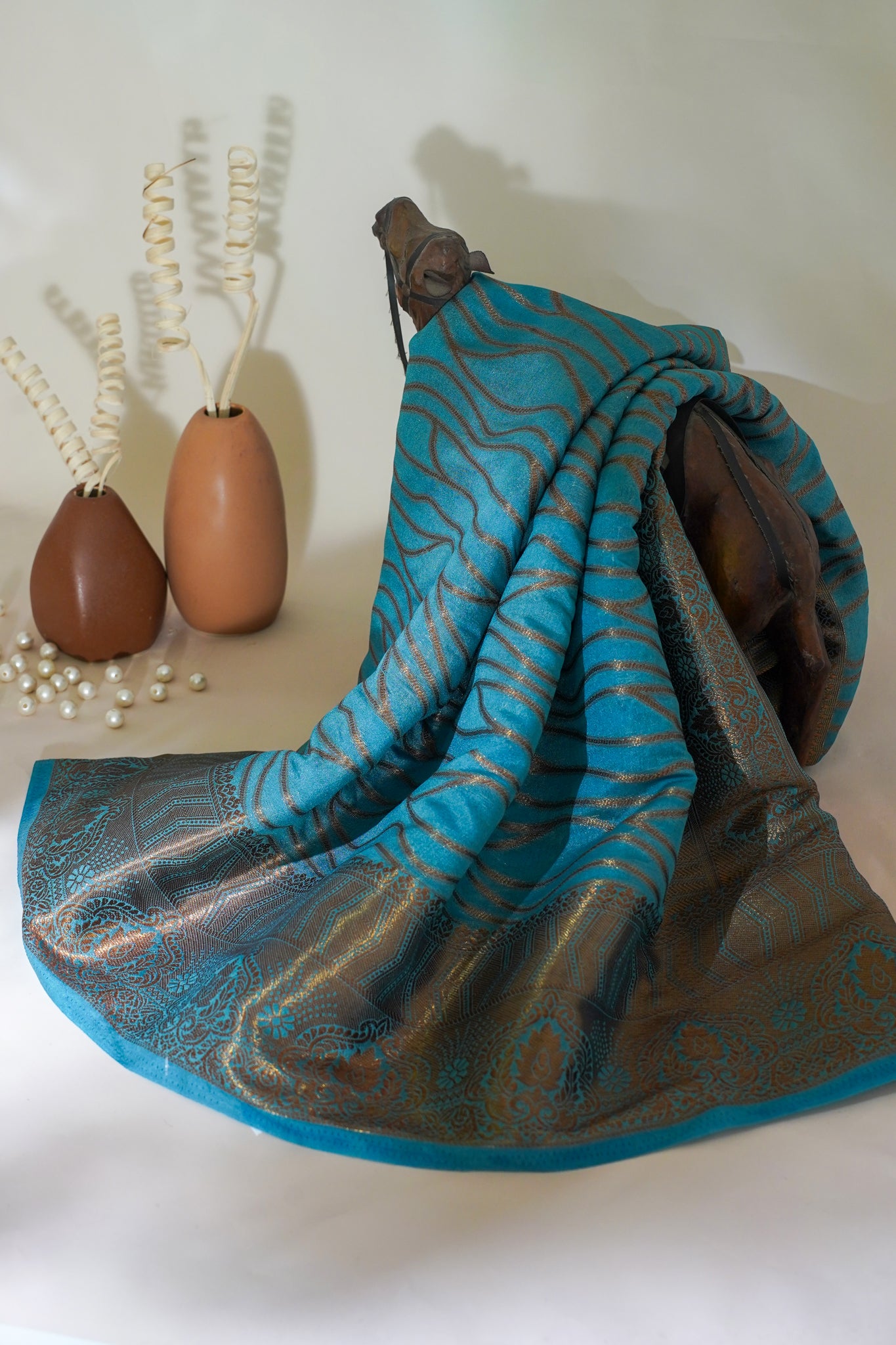Blue and gray patterned towel draped over a wooden holder with decorative vases in the background.