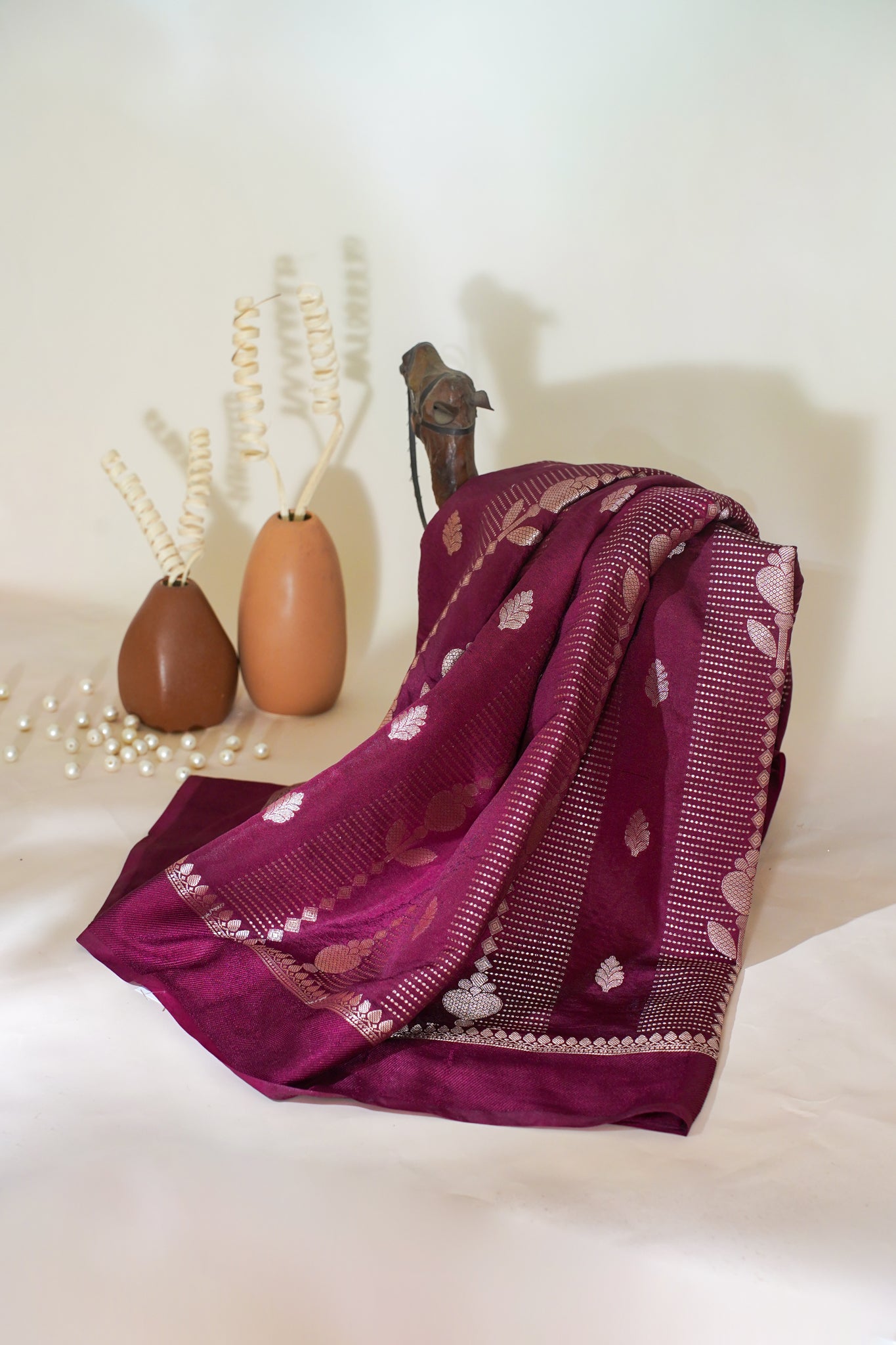 Purple scarf with heart patterns on a white surface with decorative vases in the background