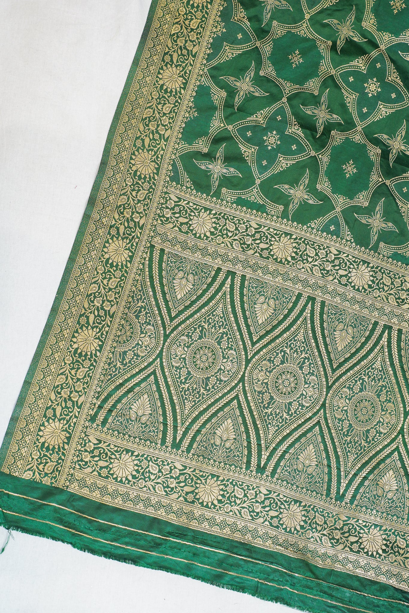 Green fabric with intricate gold patterns on a white background