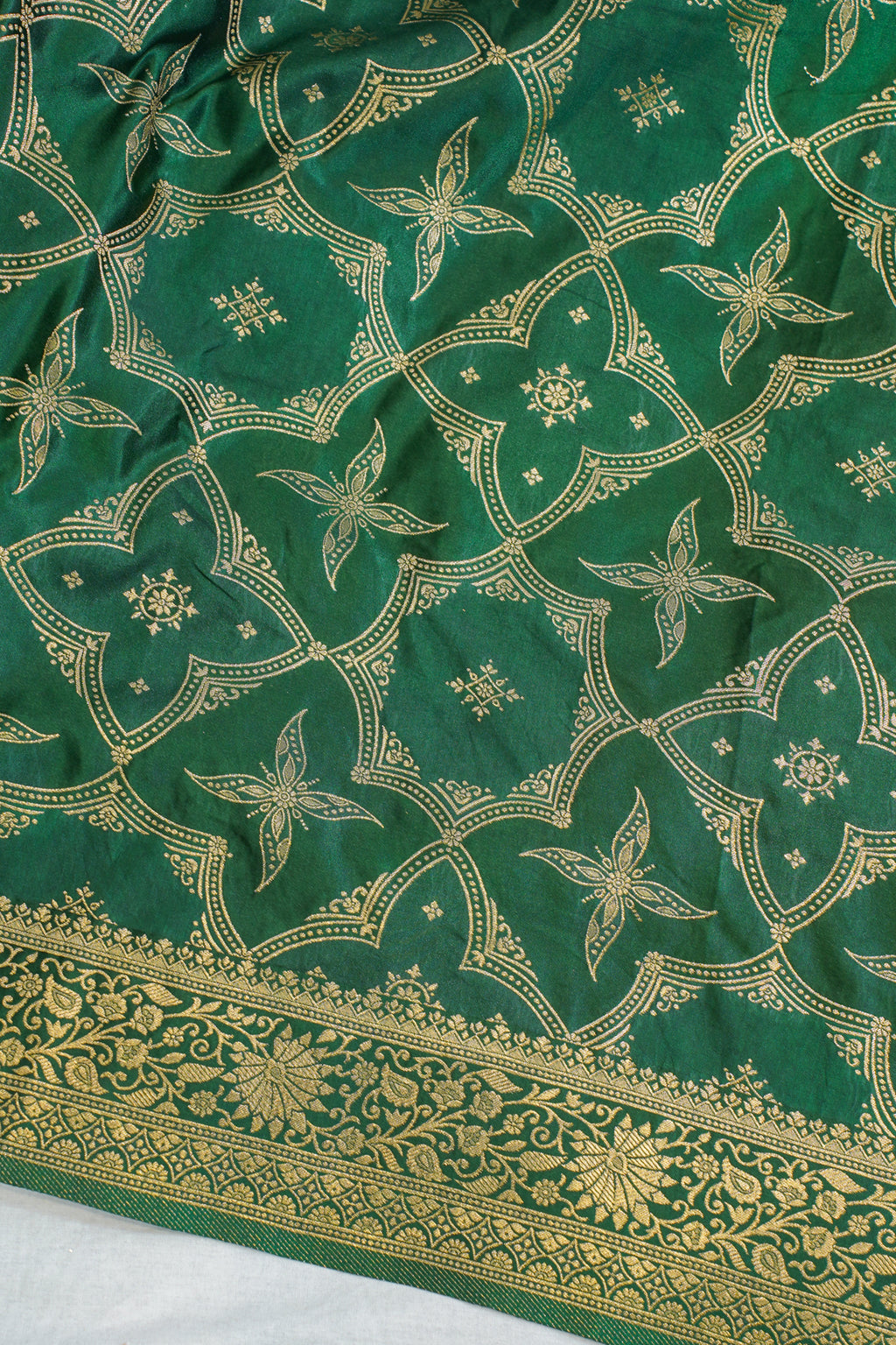 Green fabric with gold floral patterns on a white background