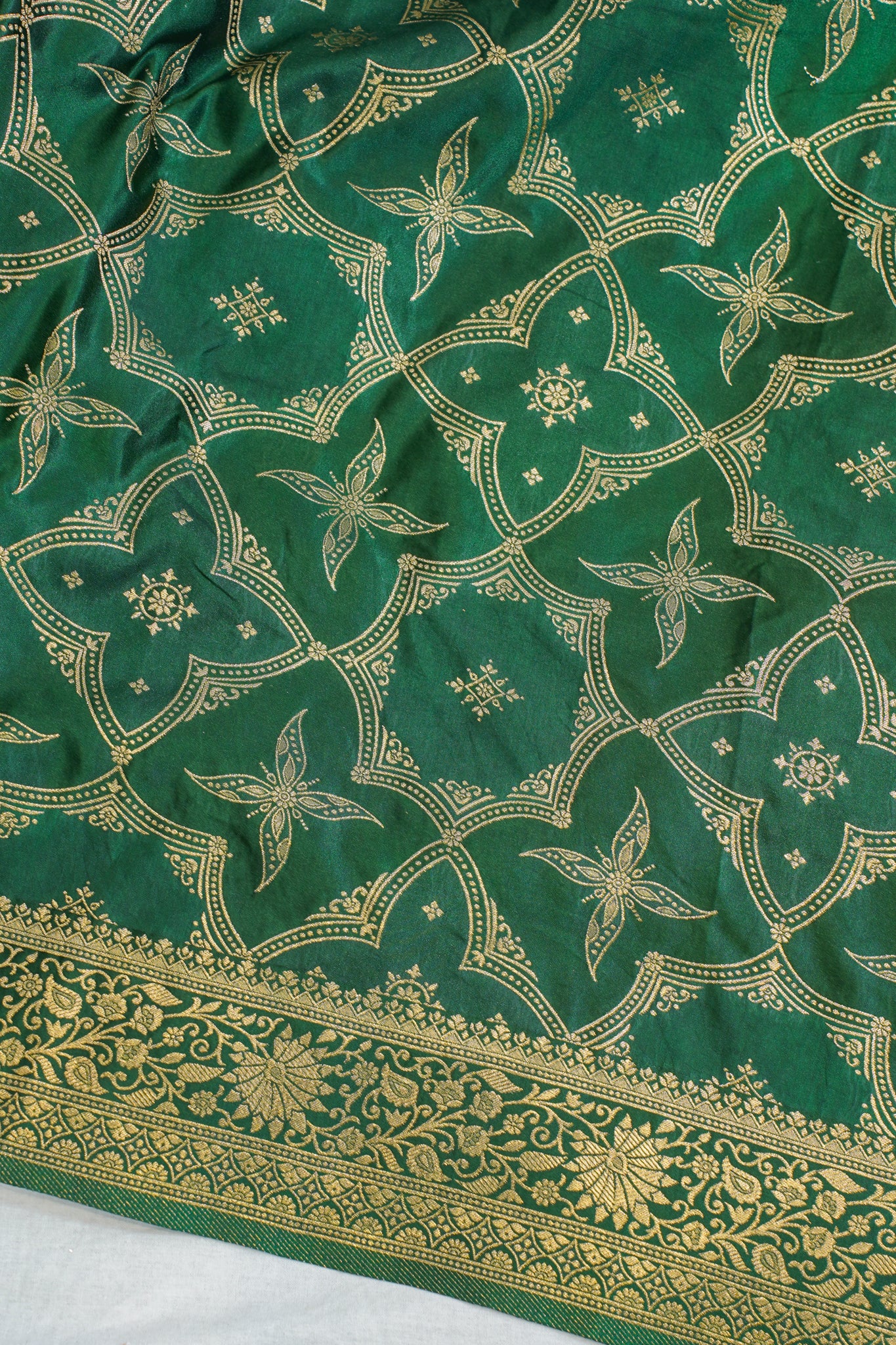 Green fabric with gold floral patterns on a white background