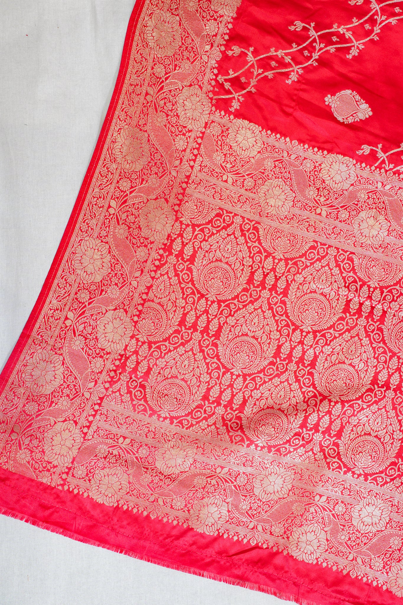 Red fabric with intricate gold patterns on a white background