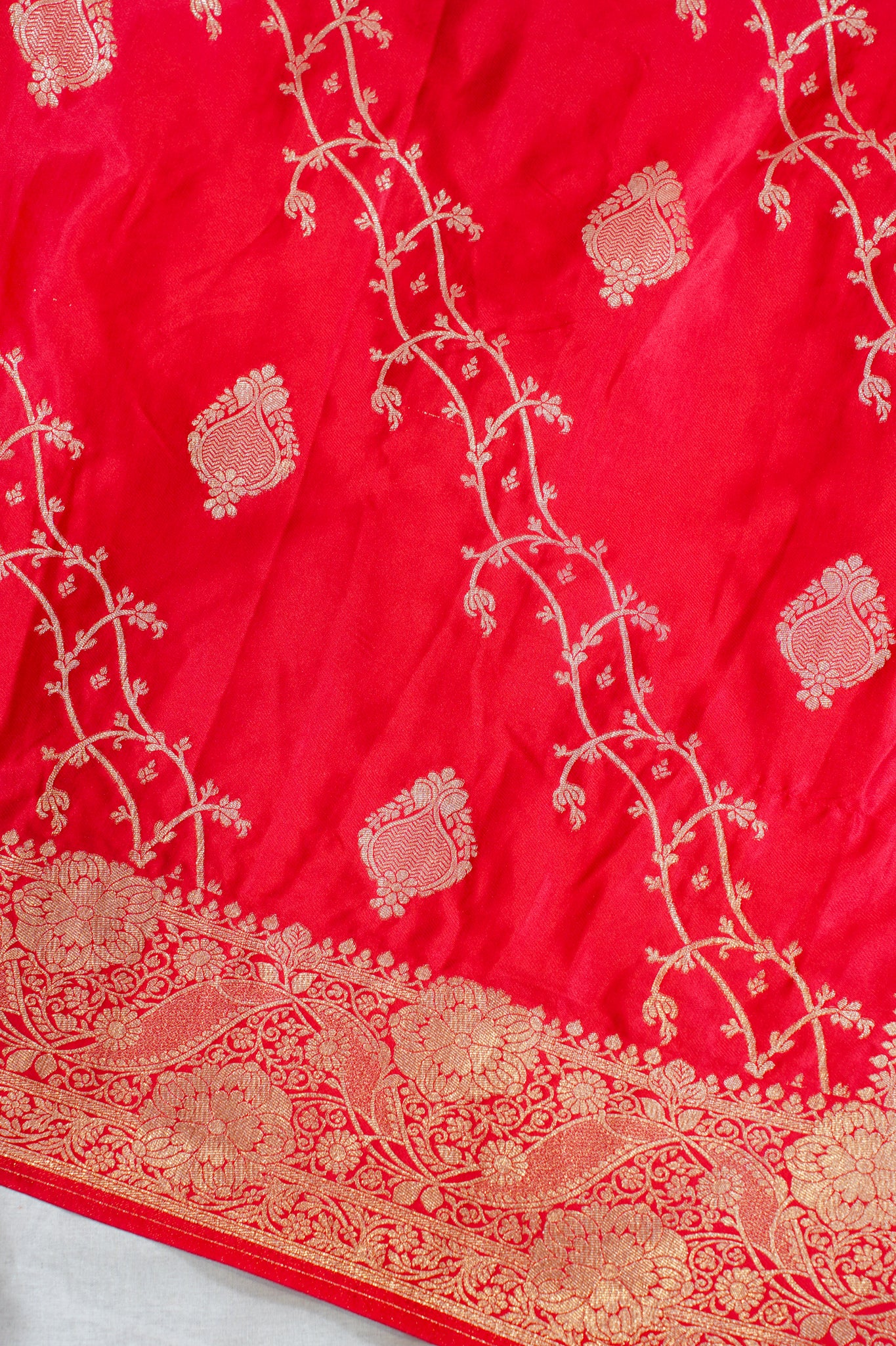 Red fabric with intricate white embroidery on a white background