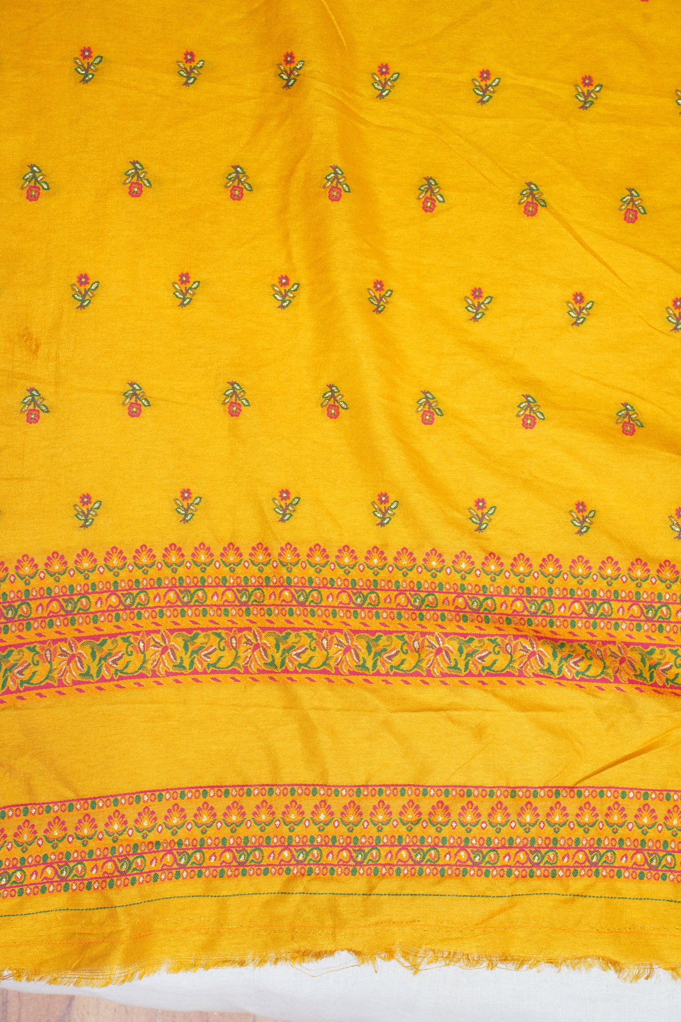 Yellow fabric with floral patterns and colorful borders on a white background