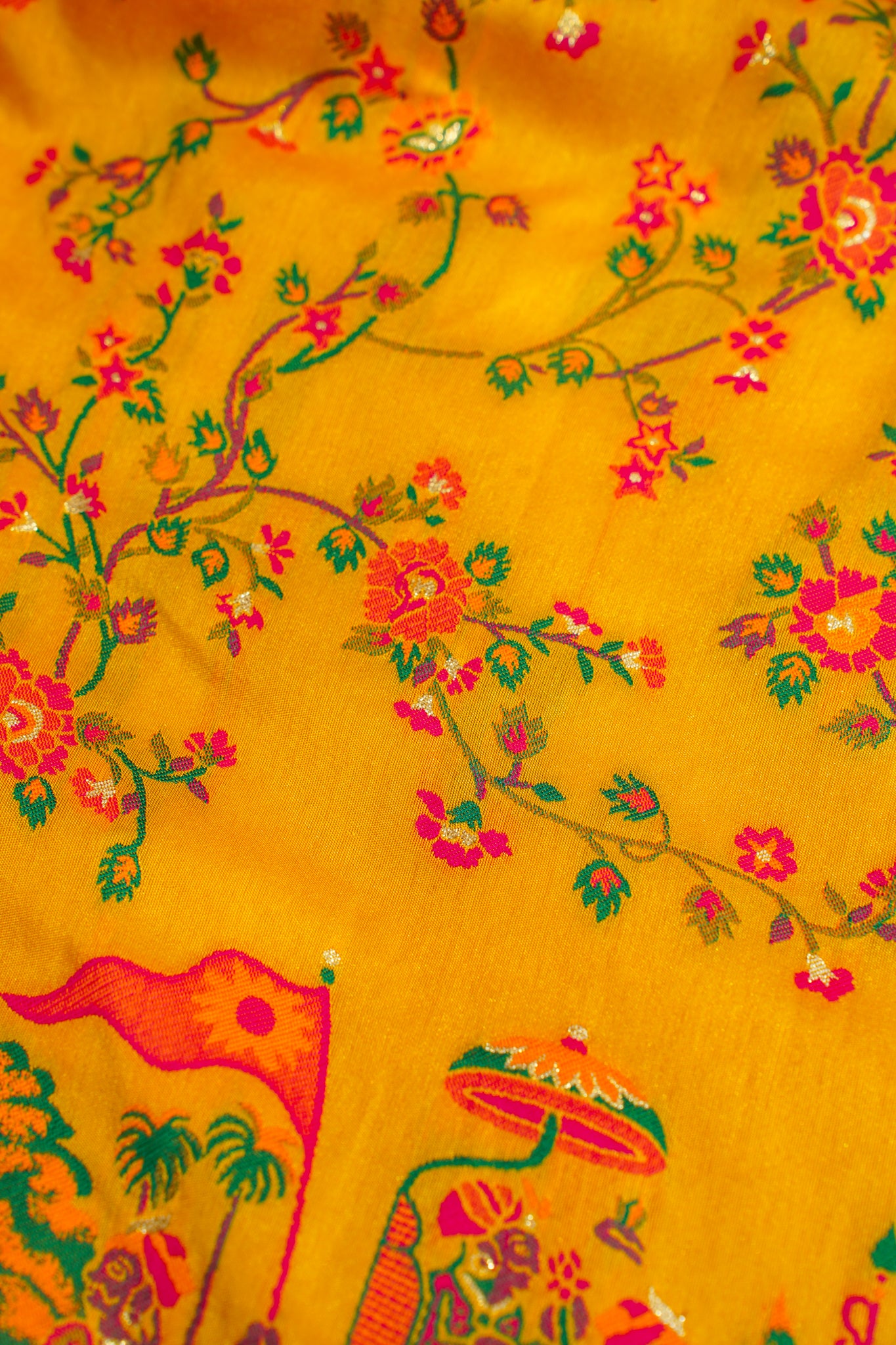 Yellow fabric with floral and elephant designs on a yellow background