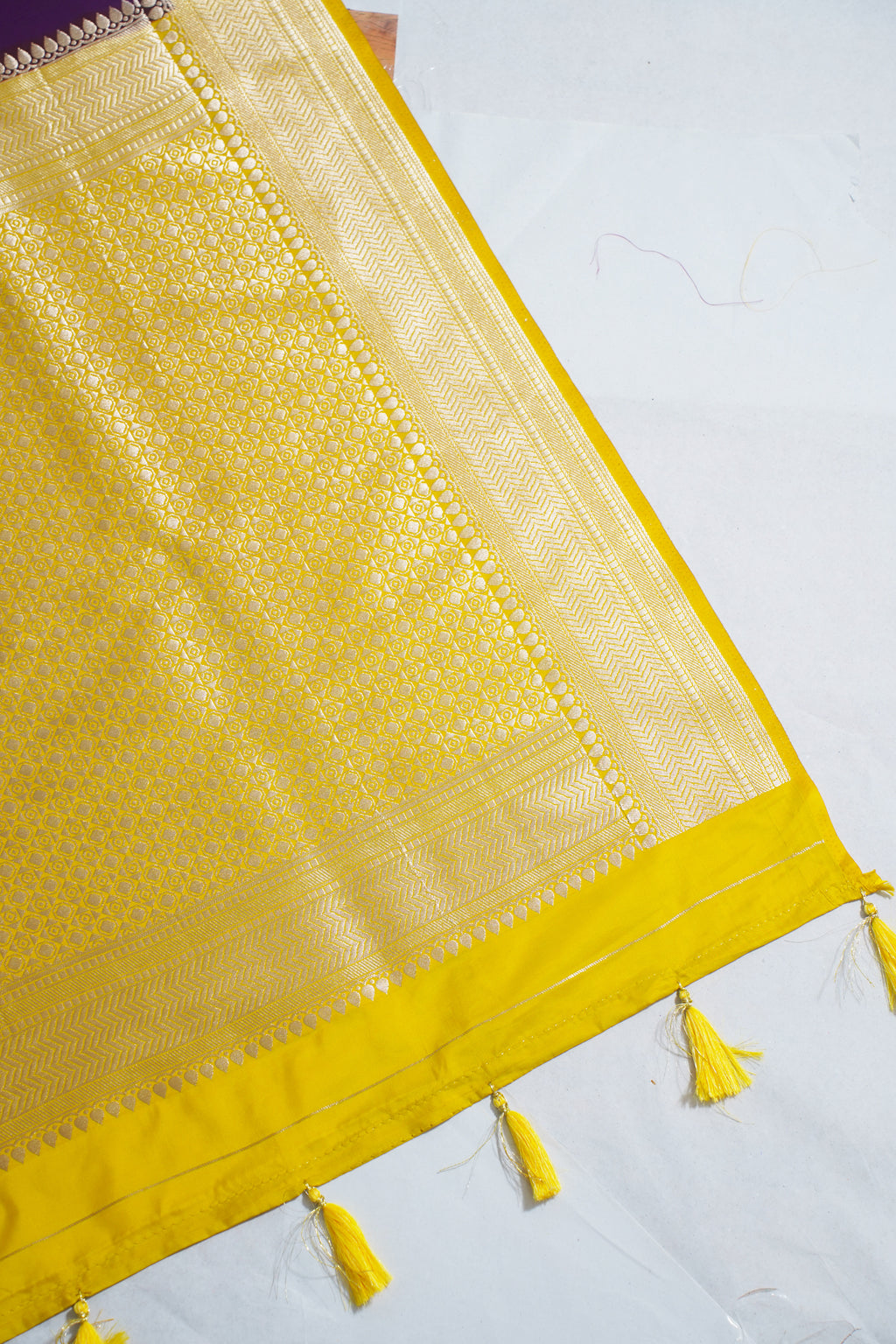 Yellow fabric with intricate patterns and tassels on a white background