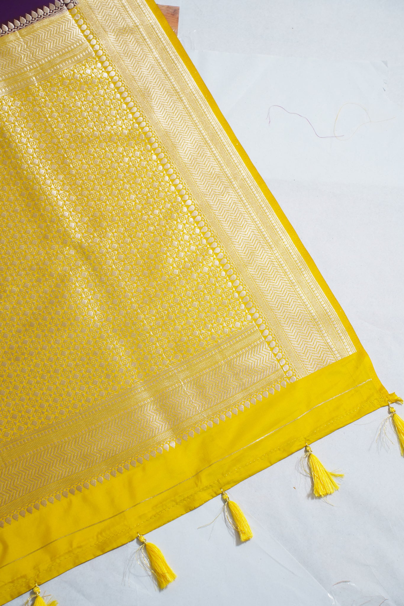 Yellow fabric with intricate patterns and tassels on a white background