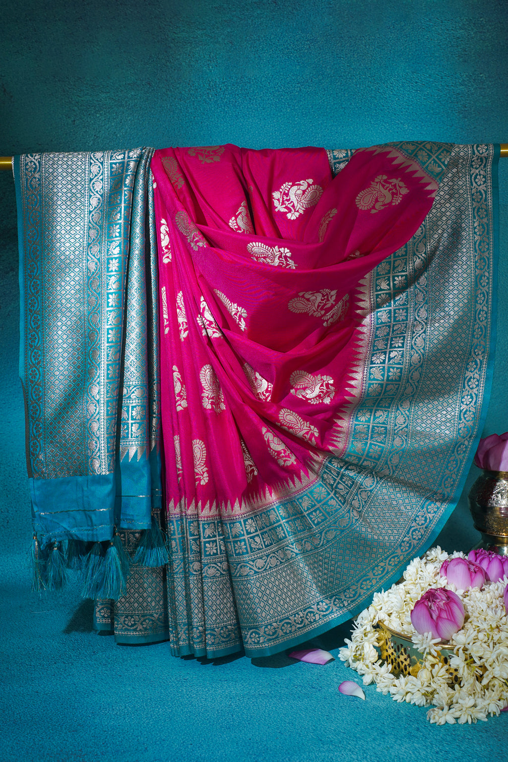 Pink saree with silver patterns draped over a blue background