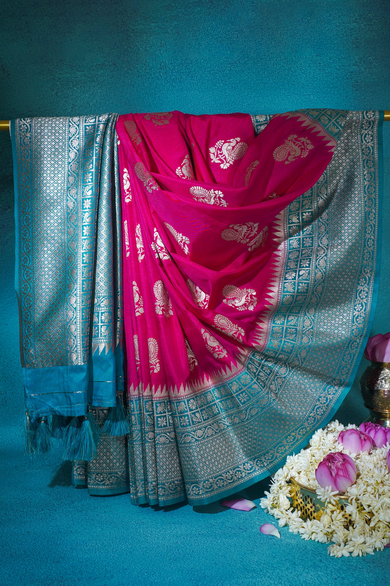 Pink saree with silver patterns draped over a blue background