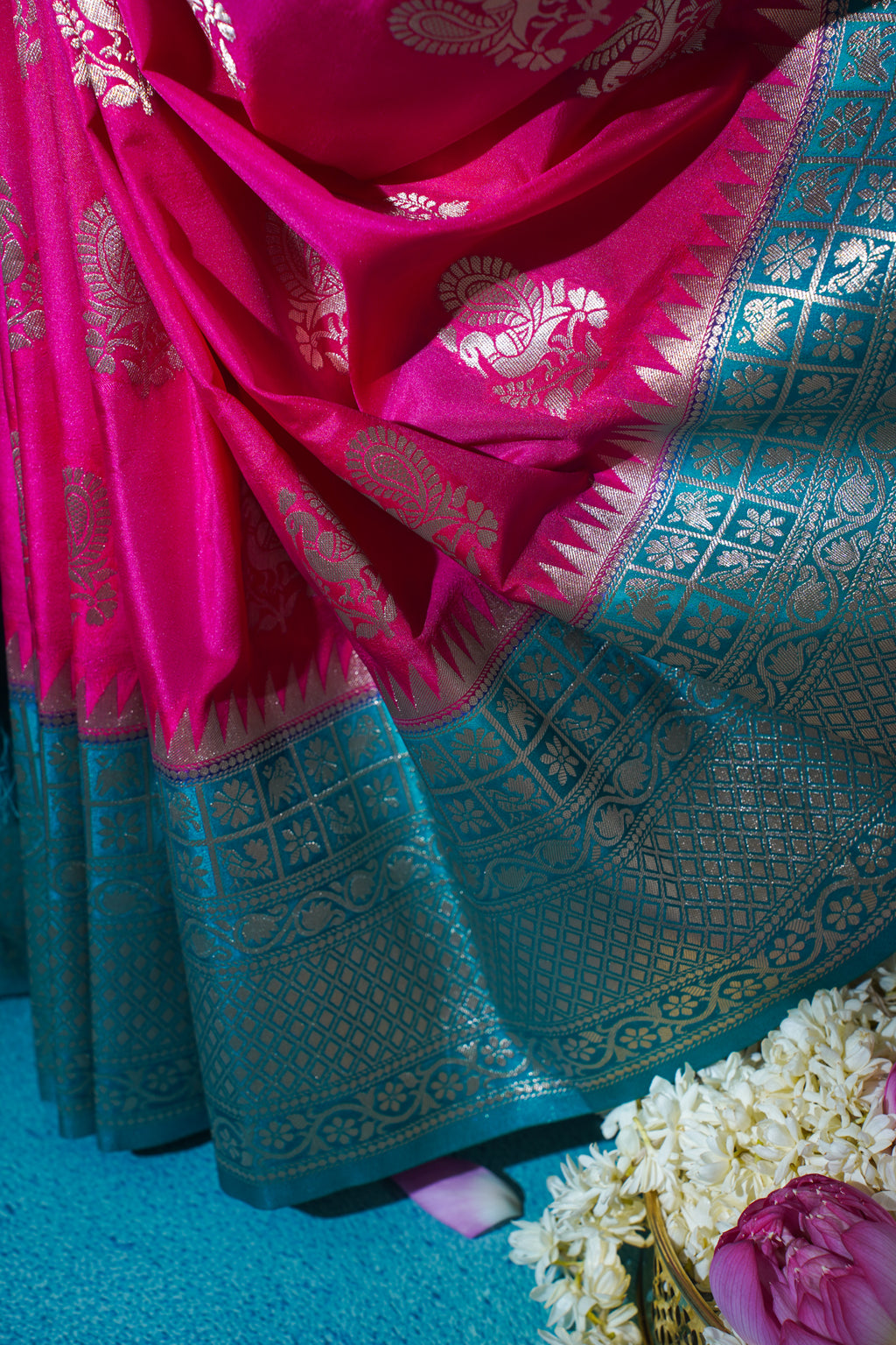 Close-up of a pink and blue saree with intricate patterns on a blue background.