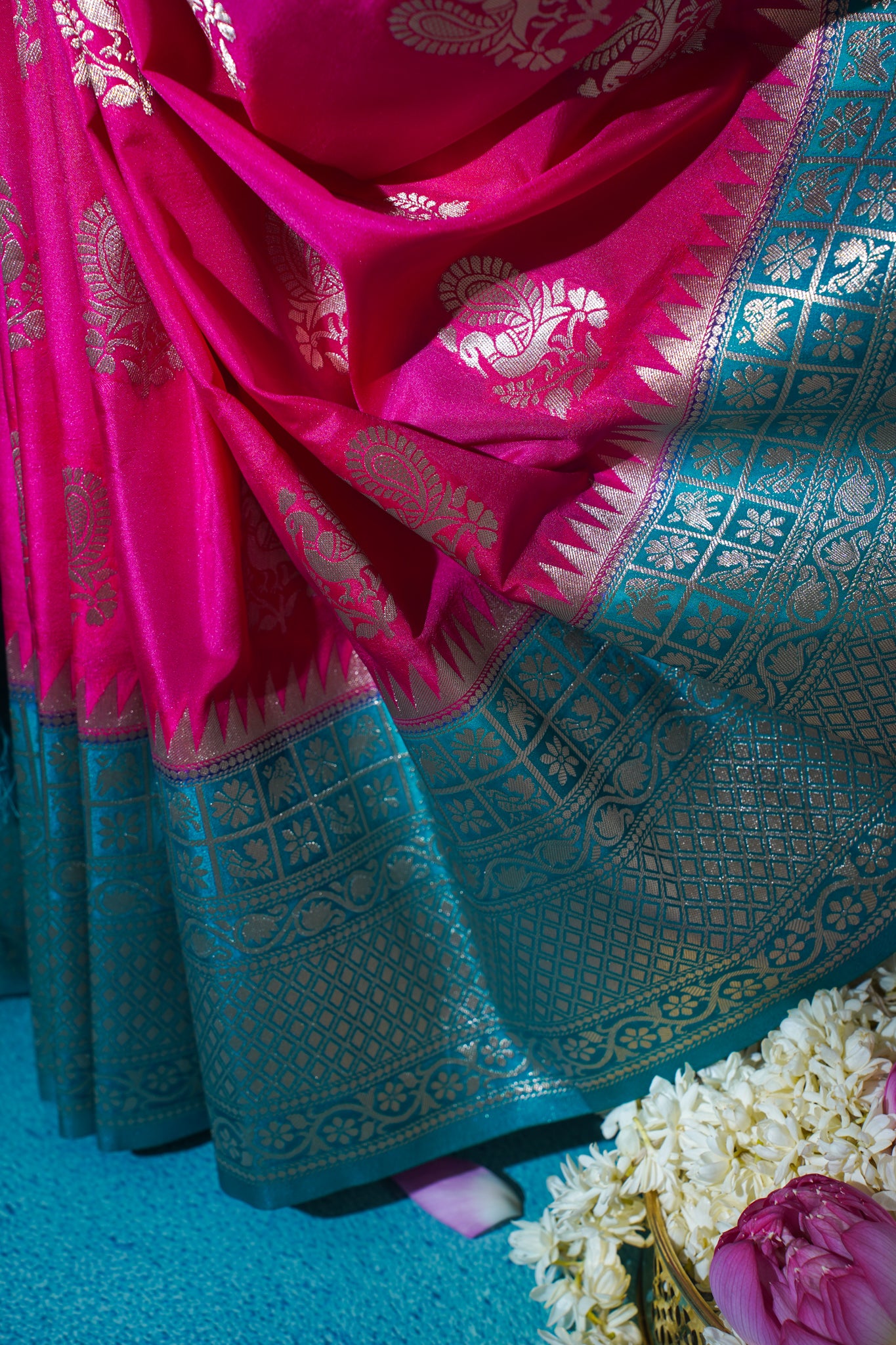 Close-up of a pink and blue saree with intricate patterns on a blue background.