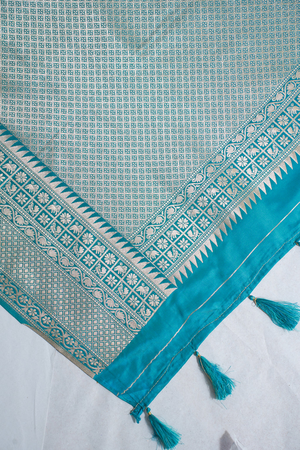 Teal and white patterned fabric with tassels on a white background