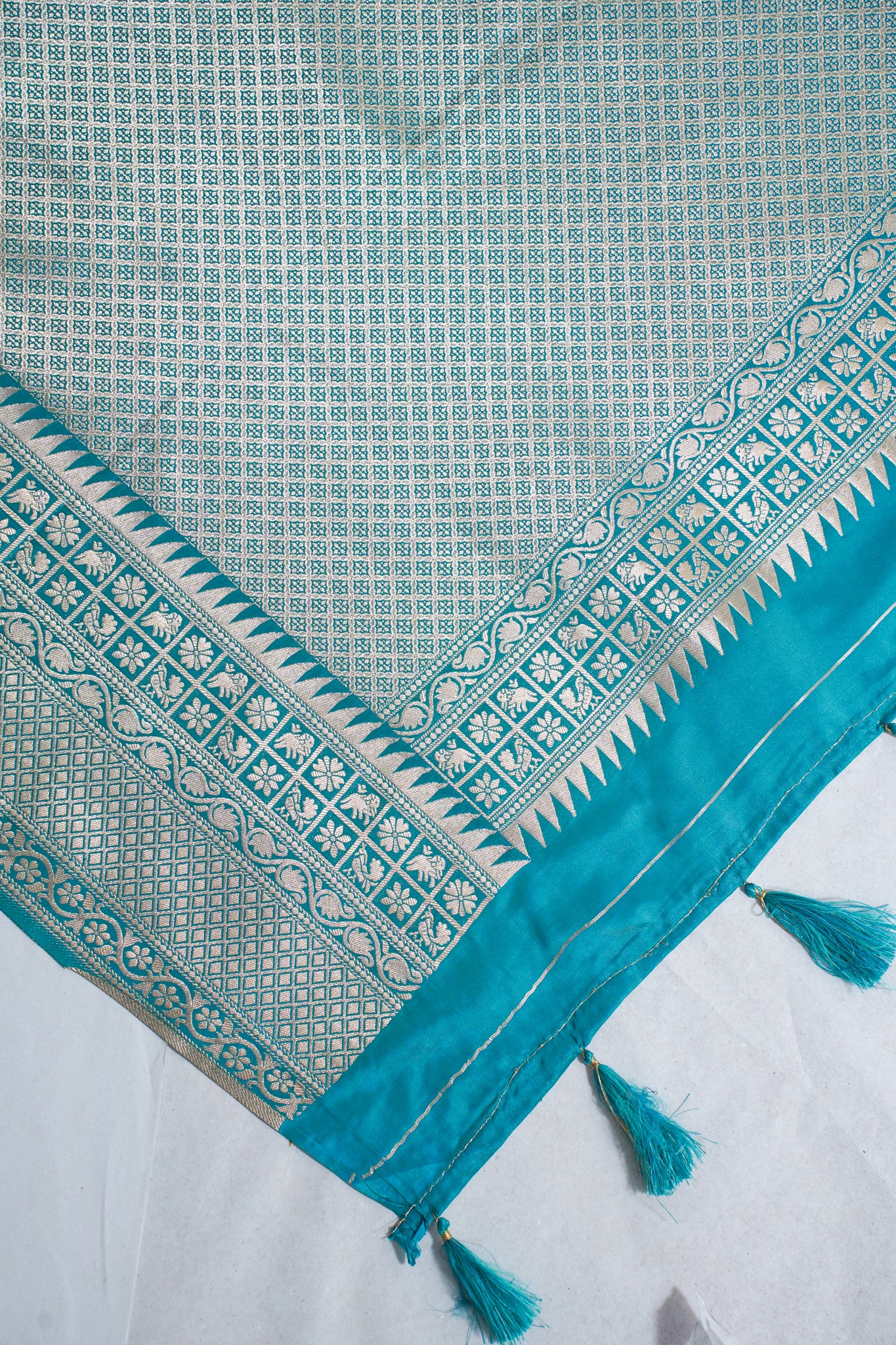 Teal and white patterned fabric with tassels on a white background