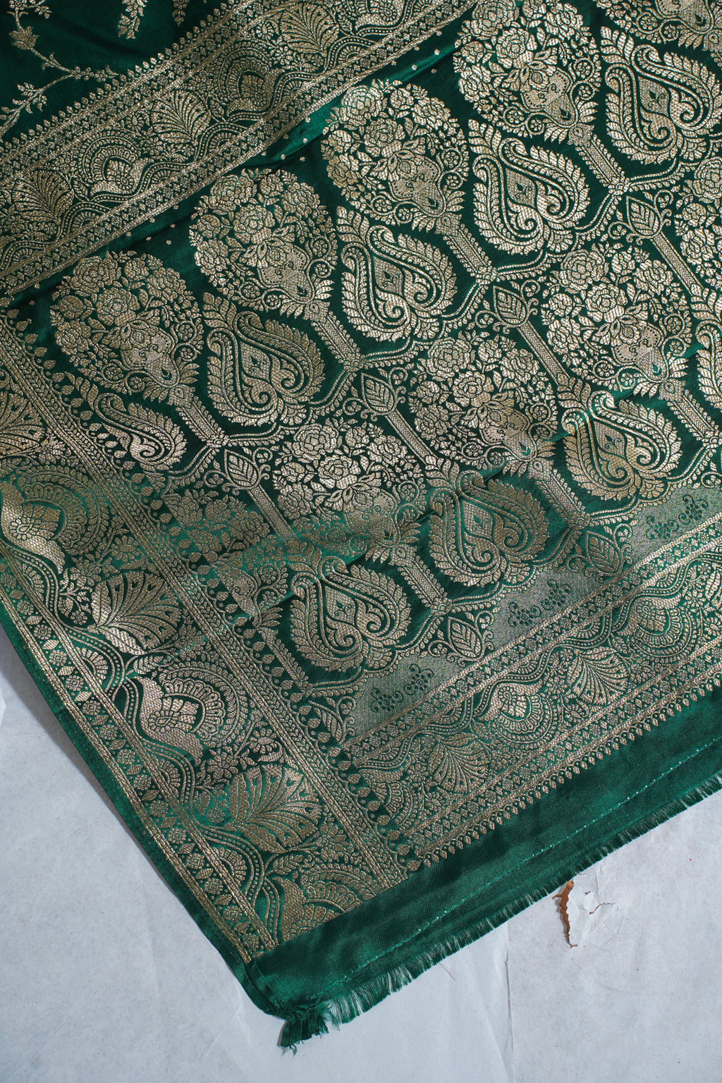 Green fabric with intricate gold patterns on a white background