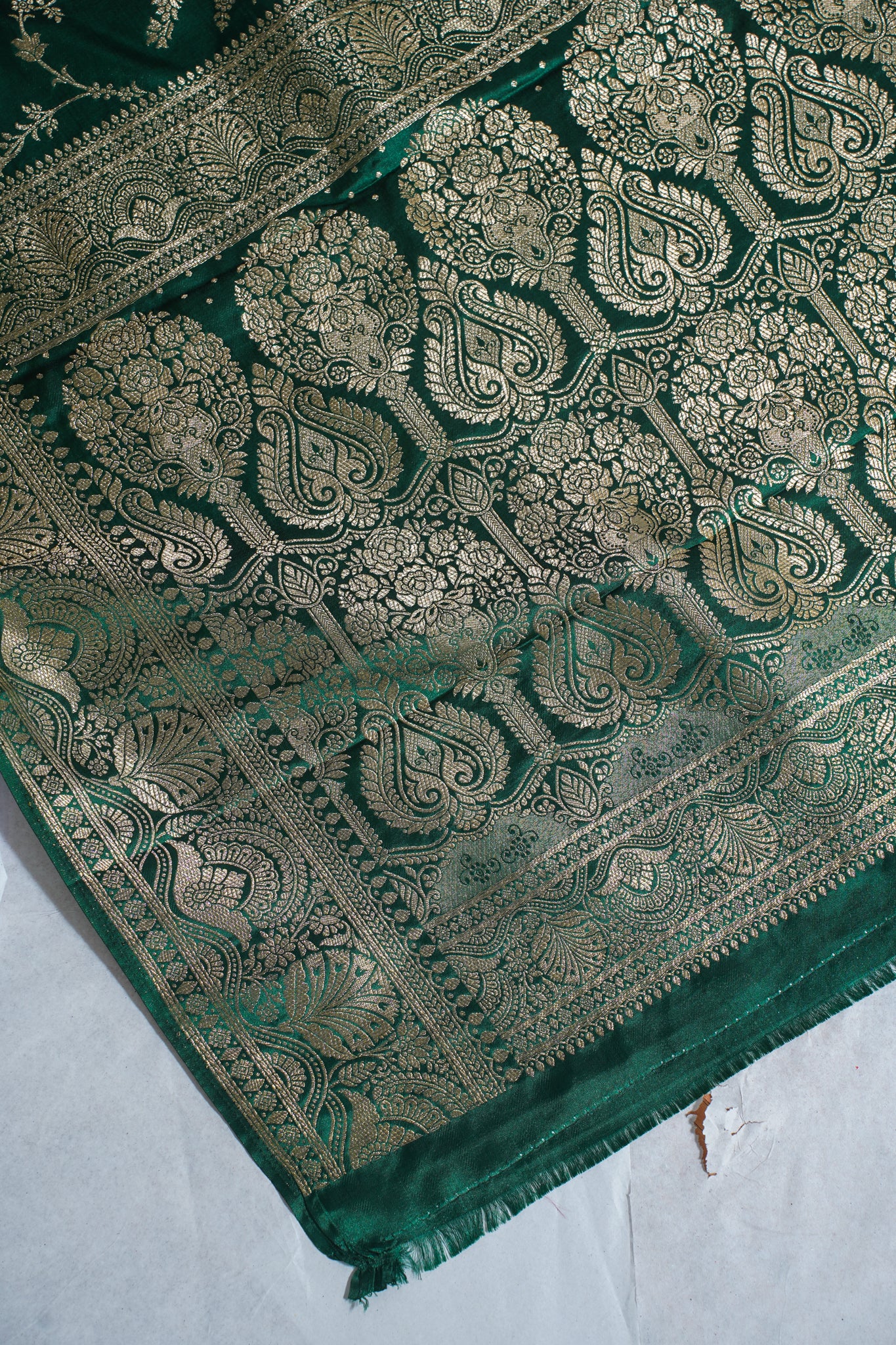 Green fabric with intricate gold patterns on a white background