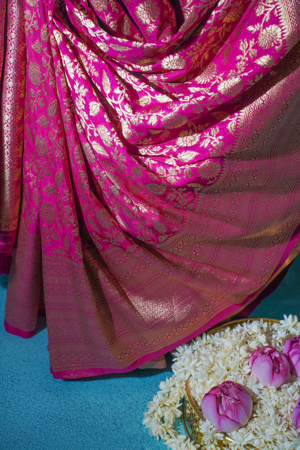 Pink saree with gold patterns on a blue background