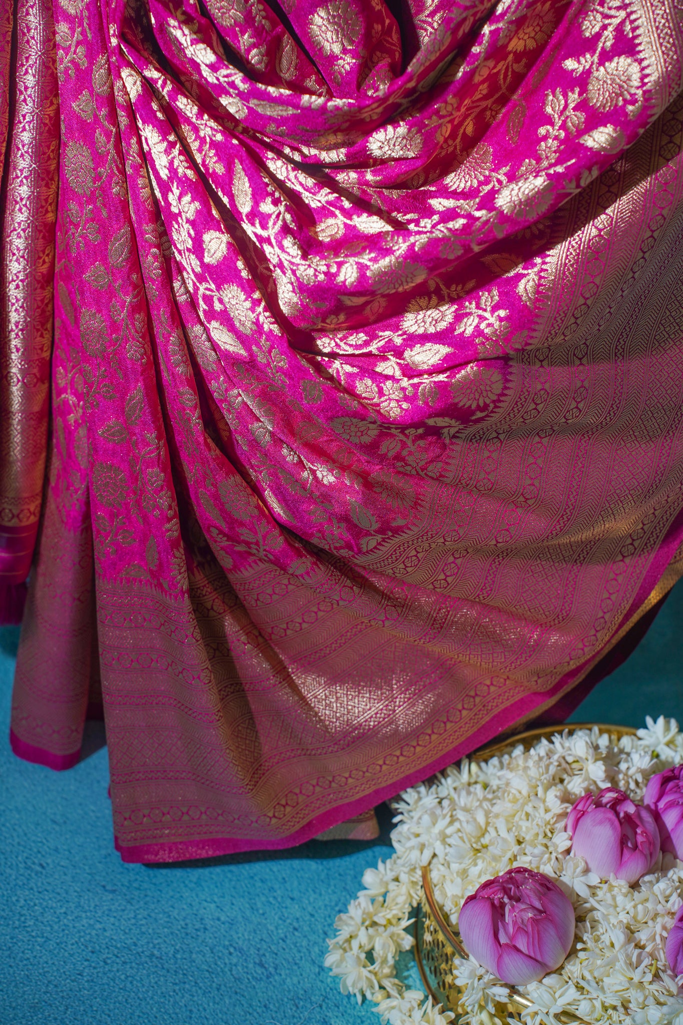 Pink saree with gold patterns on a blue background