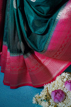Close-up of a red and green saree with floral decorations on a blue background