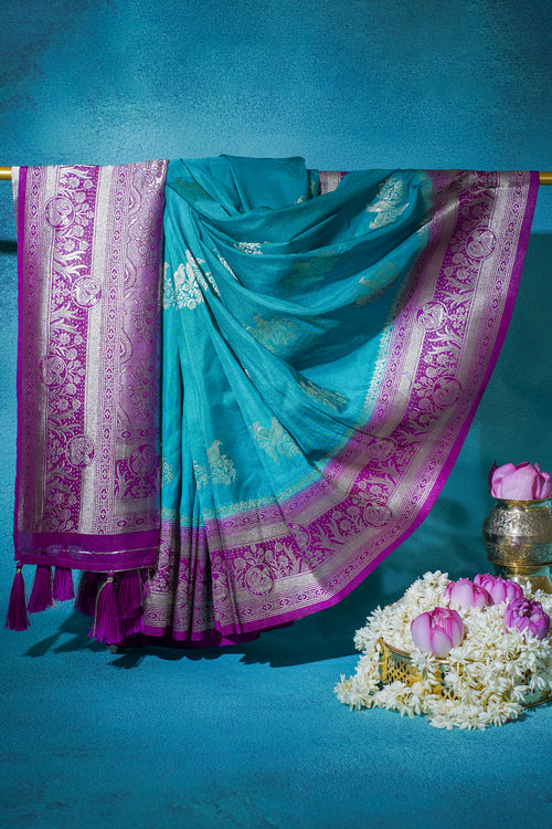 Turquoise saree with pink border on a blue background