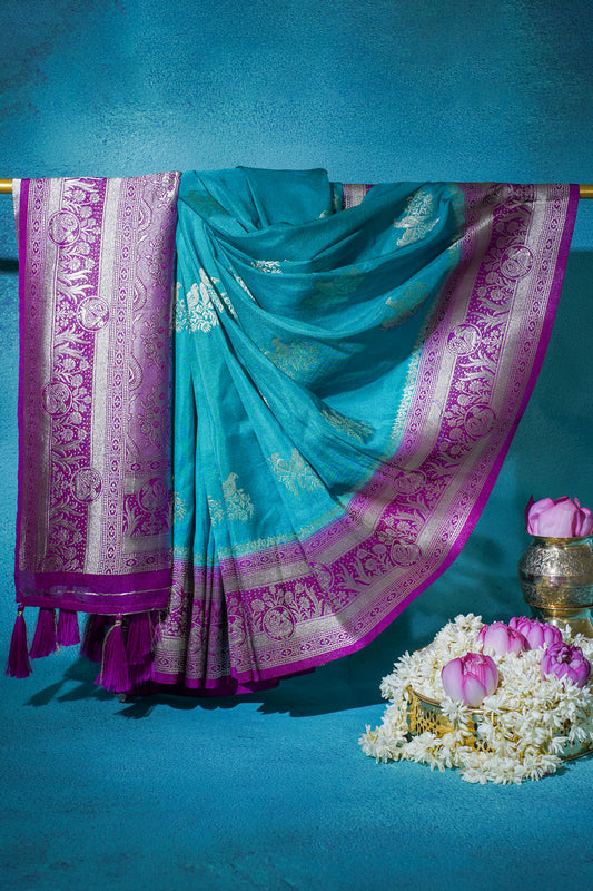 Turquoise saree with pink border on a blue background