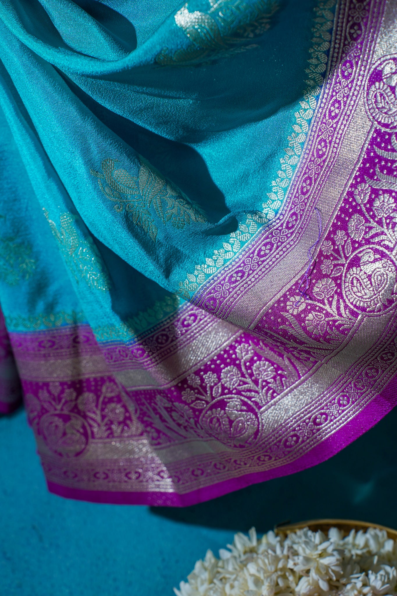 Turquoise and purple saree with intricate patterns on a blue background