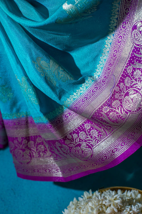 Turquoise and purple saree with intricate patterns on a blue background