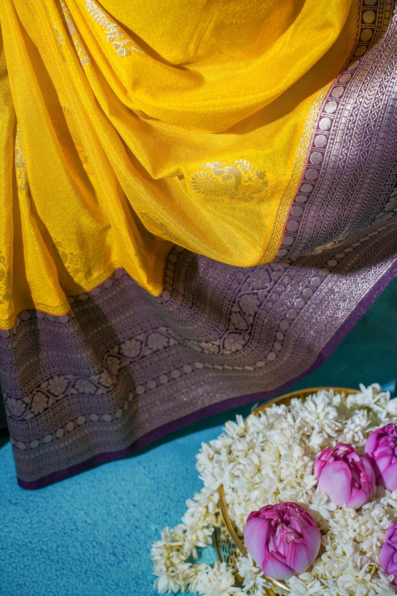 Yellow and purple saree with floral decorations on a blue surface