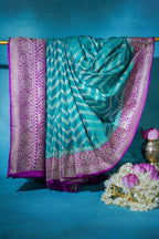 Turquoise saree with pink border on a blue background