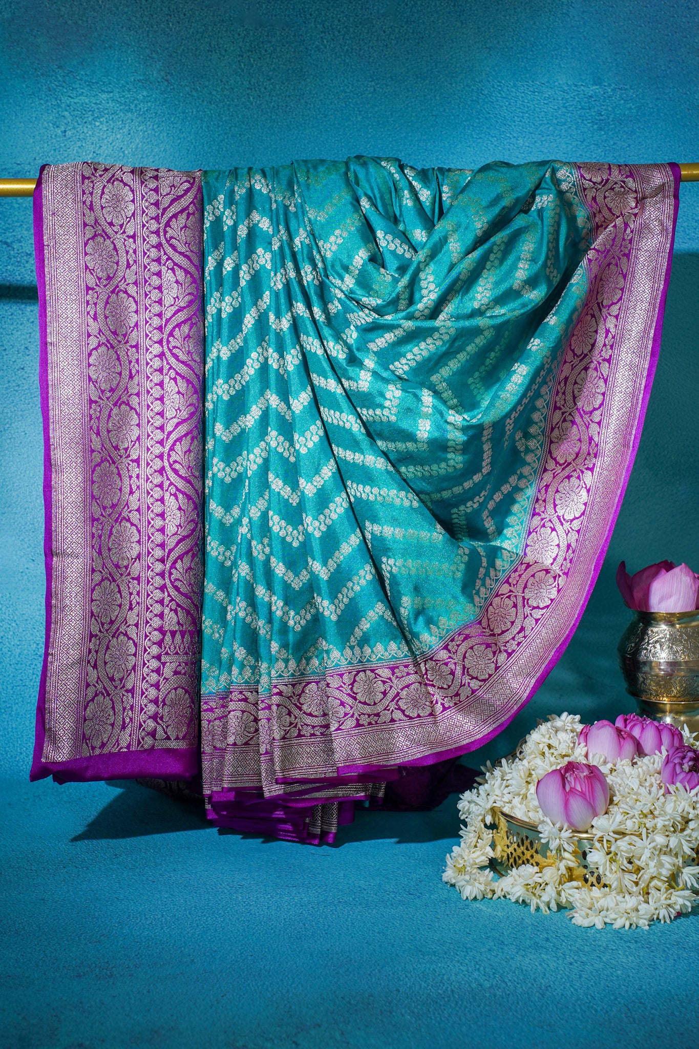 Turquoise saree with pink border on a blue background