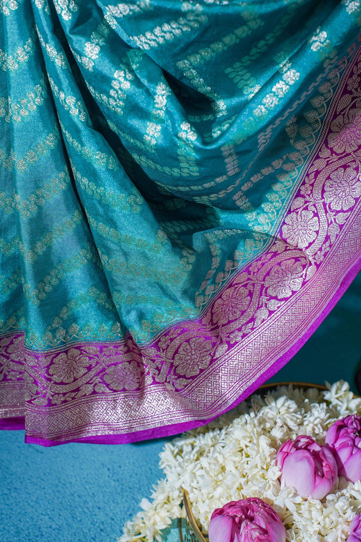 Turquoise saree with pink border on a blue background