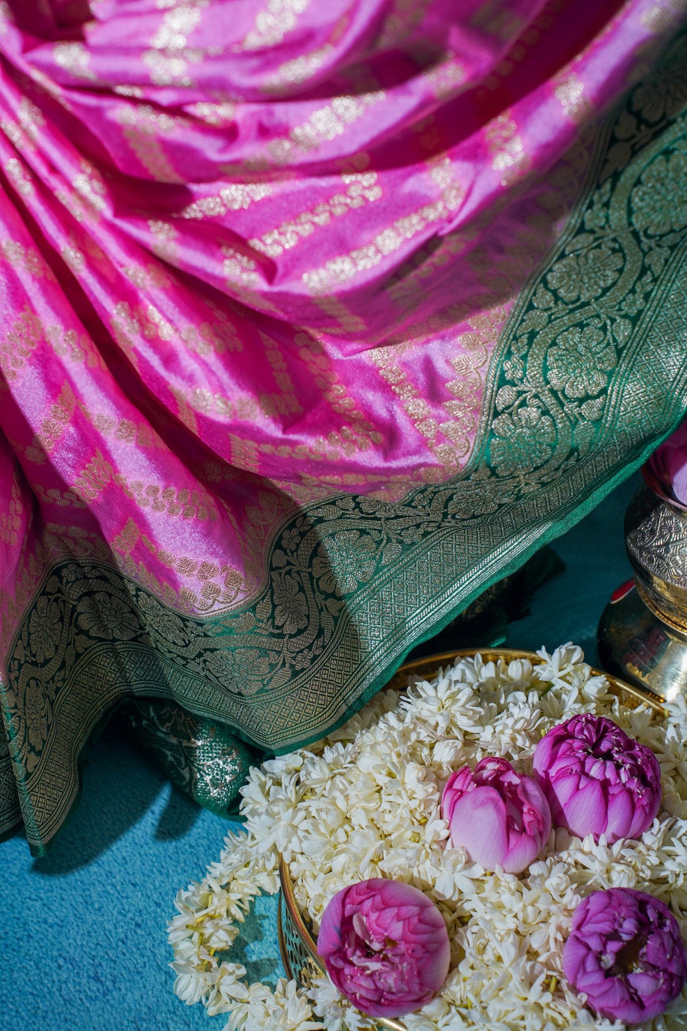 Pink and green saree with purple flowers and white rice on a blue surface