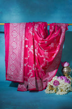 Pink saree with white patterns draped over a rod against a blue background