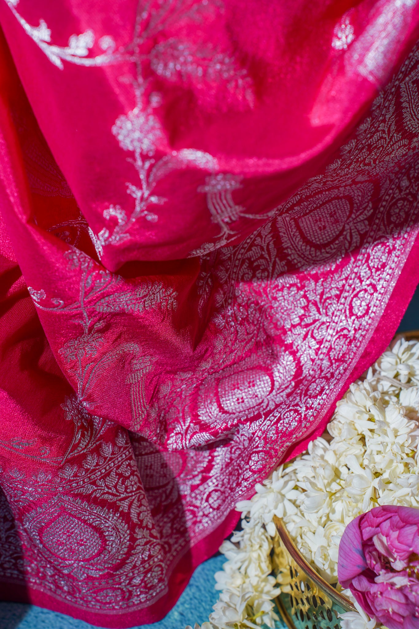 Close-up of a red saree with white patterns on a floral background