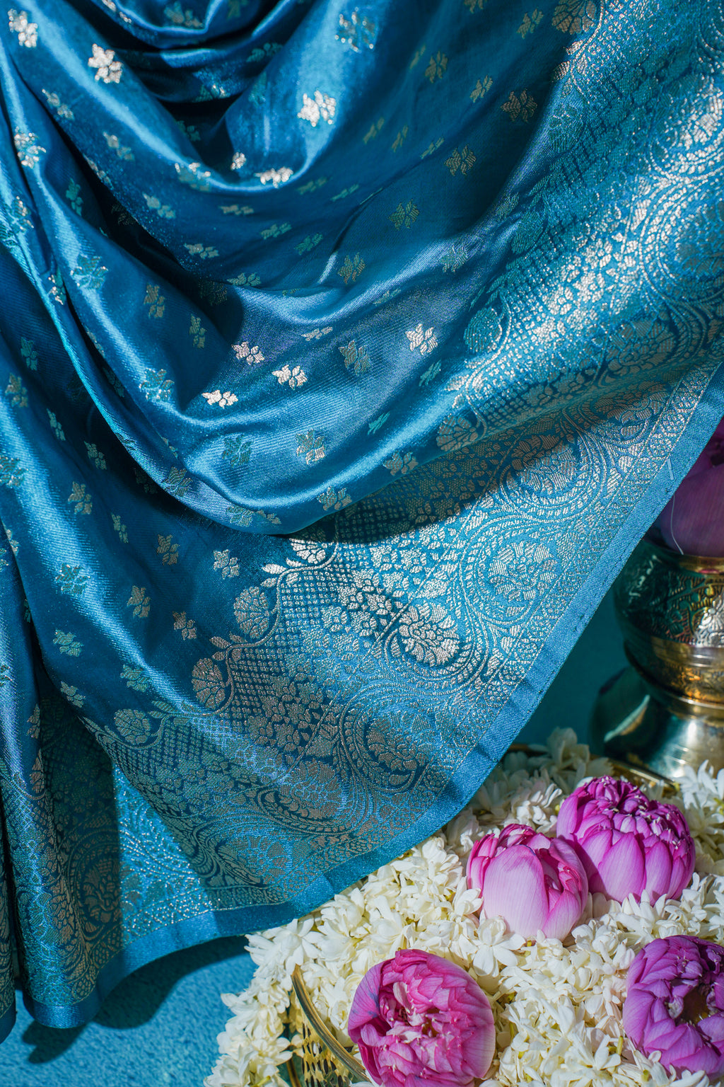 Blue fabric with floral patterns draped over a floral arrangement.