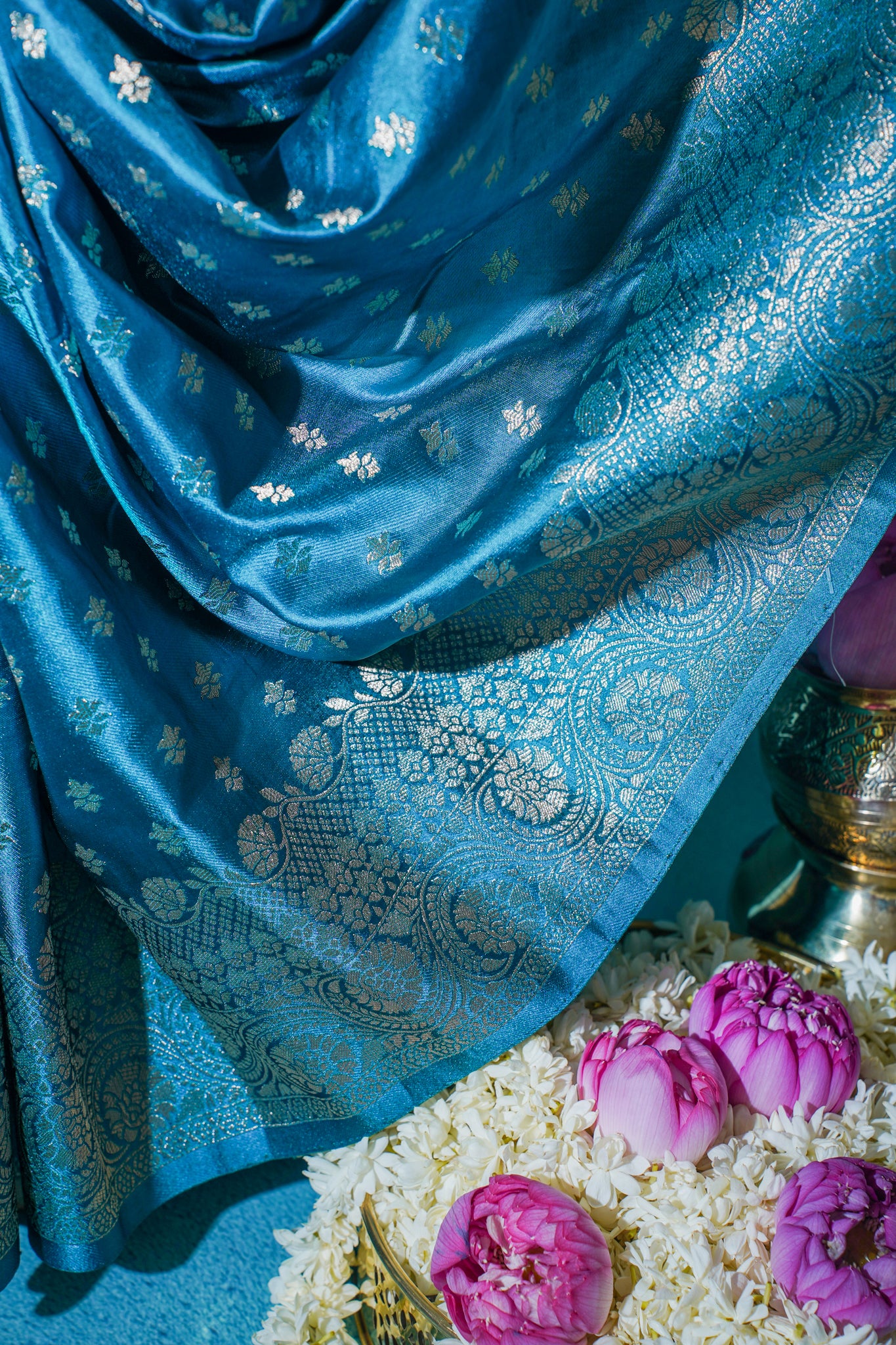 Blue fabric with floral patterns draped over a floral arrangement.