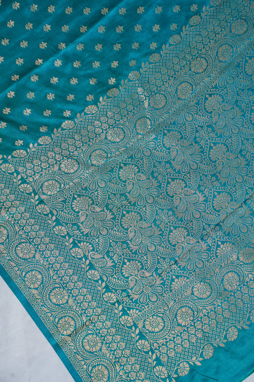 Teal fabric with intricate gold patterns on a white background