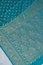 Teal fabric with intricate gold patterns on a white background