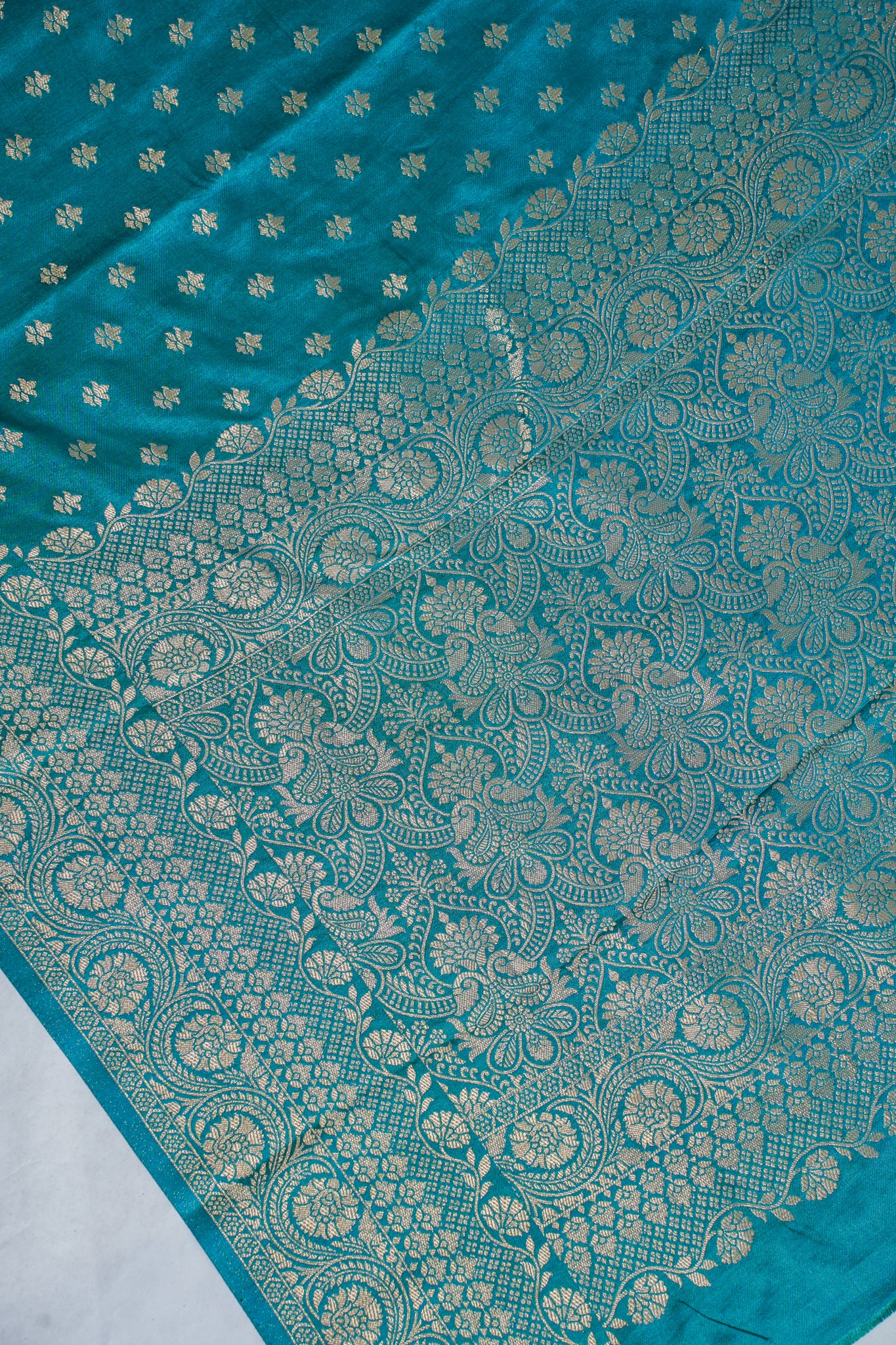 Teal fabric with intricate gold patterns on a white background