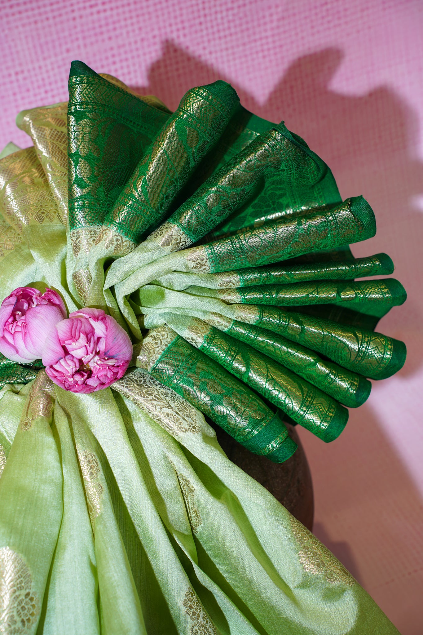 Decorative green and gold fabric with pink flowers on a pink background