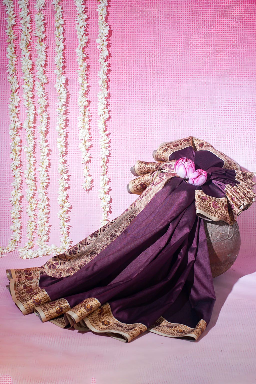 Traditional outfit with purple fabric and gold embroidery on a pink background