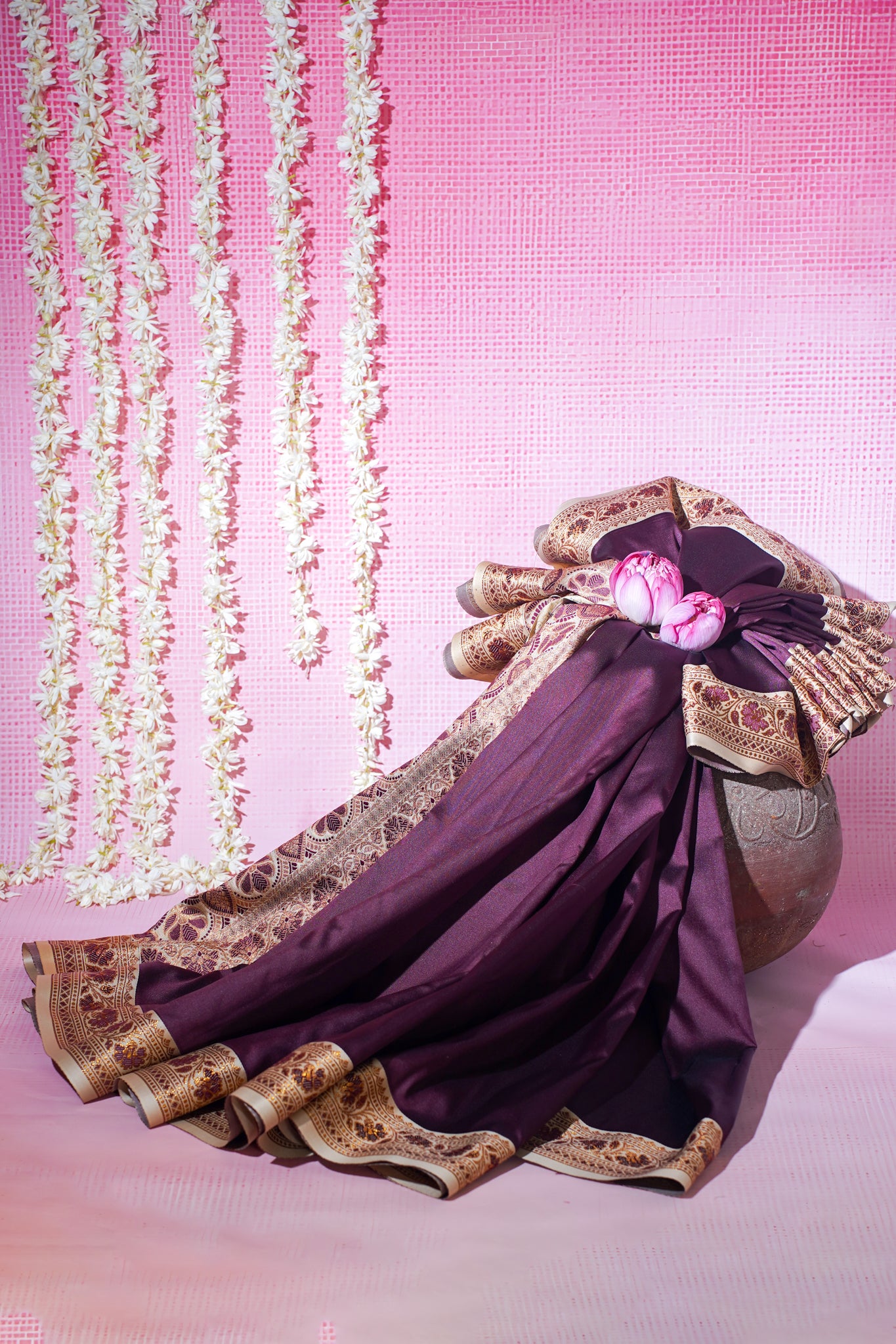 Traditional outfit with purple fabric and gold embroidery on a pink background