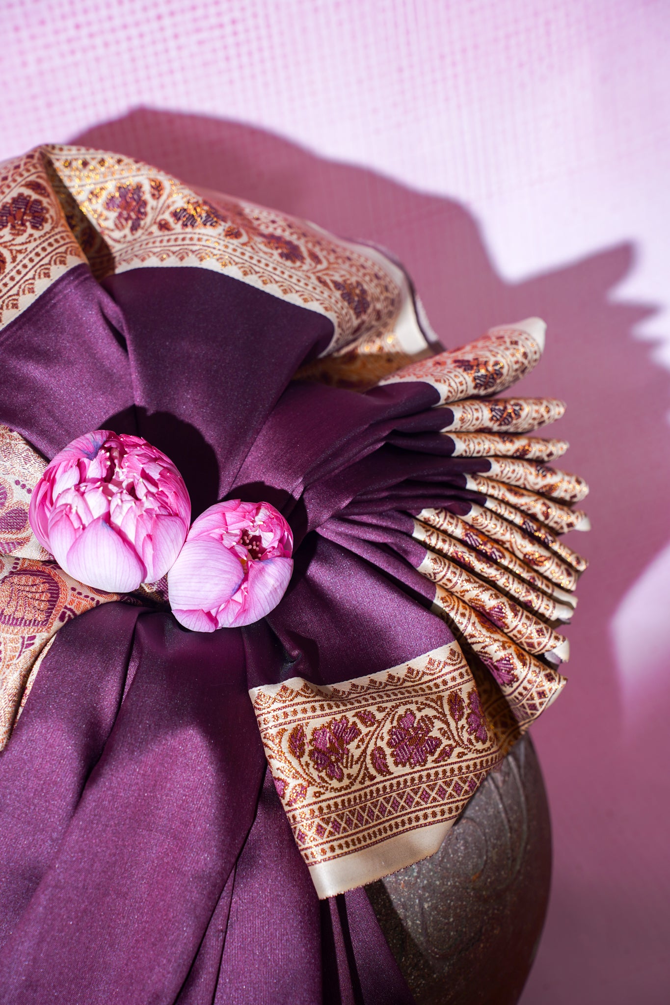 Decorative purple fabric with floral embellishments and gold embroidery on a pink background