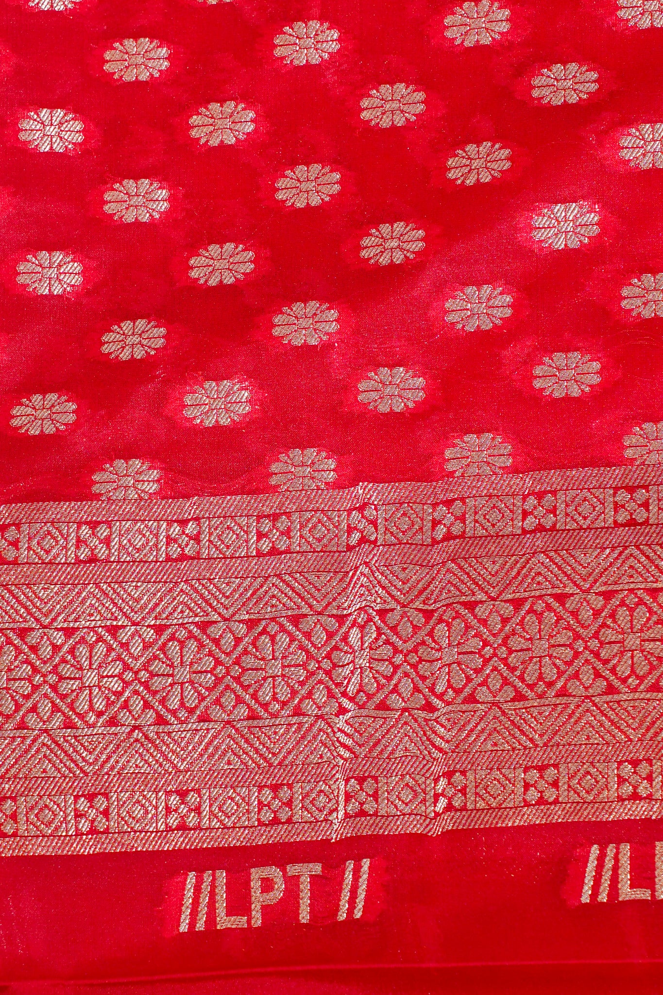 Red fabric with white floral patterns and text, possibly a textile sample.
