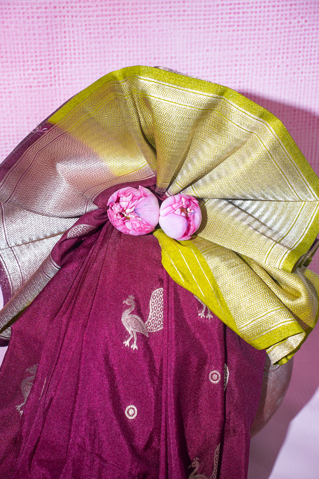 Purple saree with gold border and pink flowers on a pink background