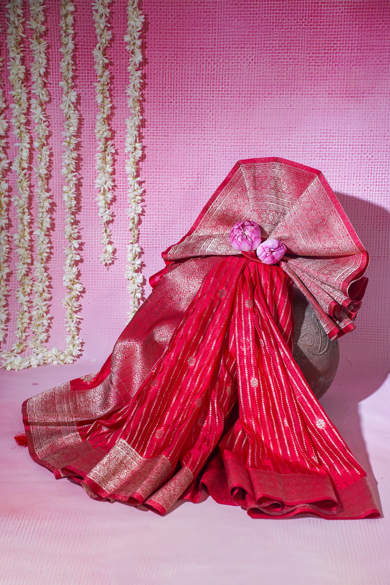 Red saree with gold border on a pink background